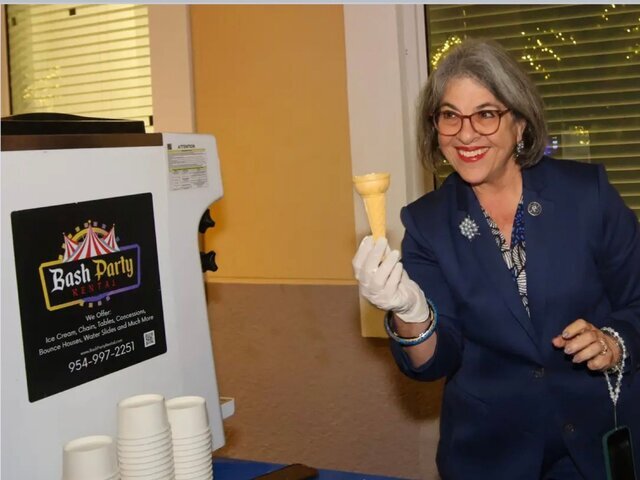 A guest holding a fresh soft serve cone next to a Bash machine at an event
