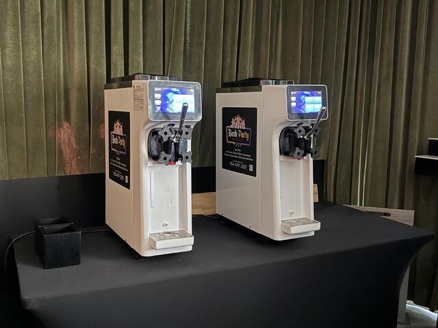 Two Bash soft serve machines set up on a black-draped table at an event venue